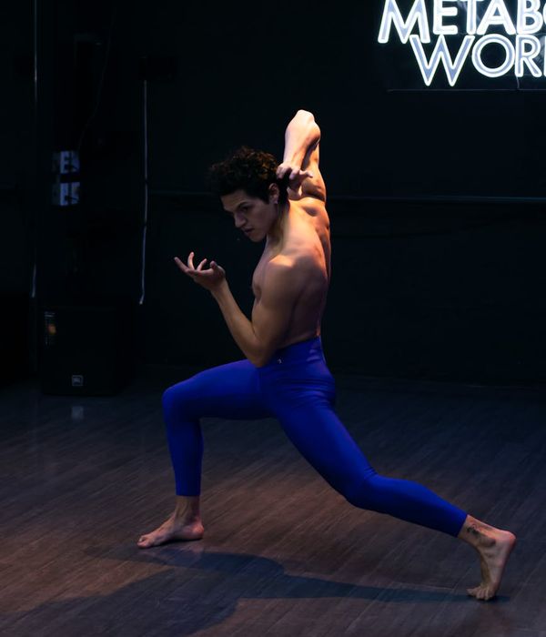 Man performing controlled strength movements in a dark studio